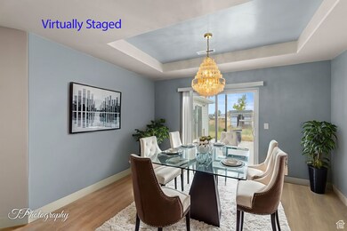 Dining space with a tray ceiling, light wood-type flooring, and a chandelier