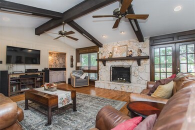 Moving into the Family room is a beautiful STONE wood burning fireplace with French doors leading out into the backyard