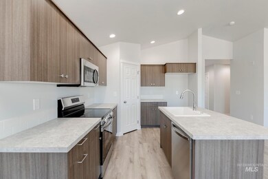 Kitchen featuring appliances with stainless steel finishes, modern cabinets, light wood-style flooring, light countertops, and a center island with sink