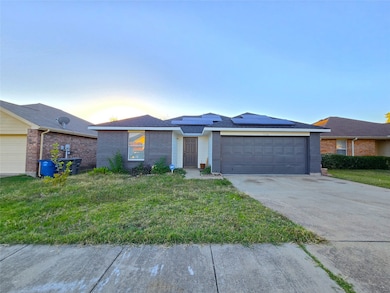 Ranch-style house with solar panels, a front yard, brick siding, concrete driveway, and roof with shingles