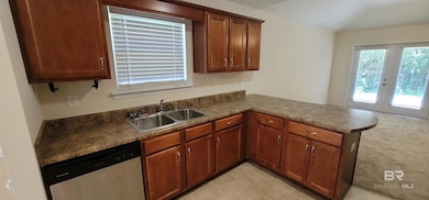 Kitchen with a peninsula, french doors, dishwasher, dark countertops, and light colored carpet