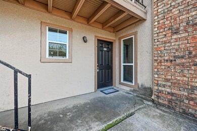 Doorway to property featuring a patio, stucco siding, and brick siding