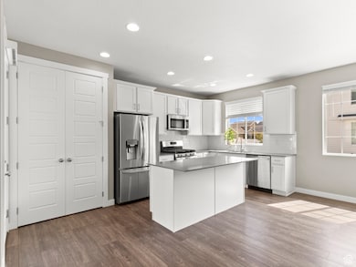 Kitchen featuring stainless steel appliances, white cabinetry, recessed lighting, dark wood-style floors, and a kitchen island