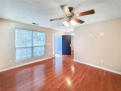Spare room featuring light wood-style floors, a ceiling fan, and baseboards