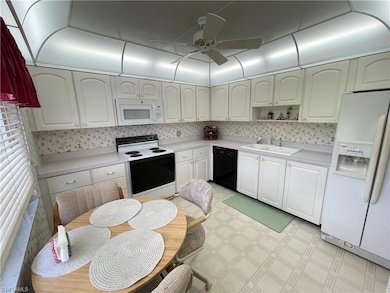 Kitchen with ceiling fan, sink, white cabinets, an