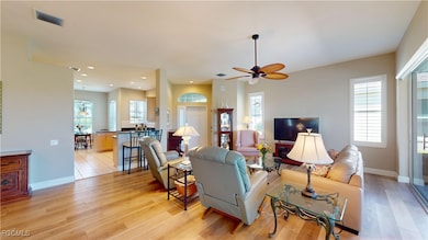 Living room with ceiling fan, light wood-style flooring, and recessed lighting
