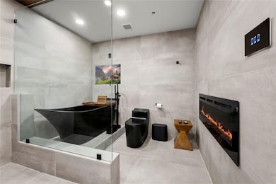 Primary bathroom featuring a color changing firepl