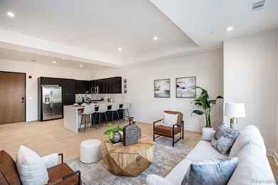 Living area with recessed lighting, light wood finished floors, and a tray ceiling