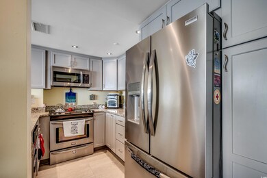 Kitchen with appliances with stainless steel finishes, light stone countertops, gray cabinetry, recessed lighting, and light tile patterned floors