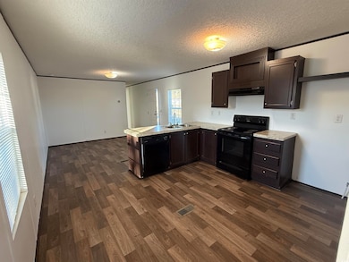 Kitchen featuring light countertops, dark brown cabinets, a peninsula, black appliances, and a textured ceiling
