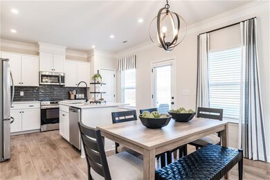 Kitchen featuring stainless steel appliances, a sink, an island with sink, light wood-style floors, and ornamental molding