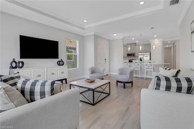 Living room featuring visible vents, a tray ceiling, and ornamental molding