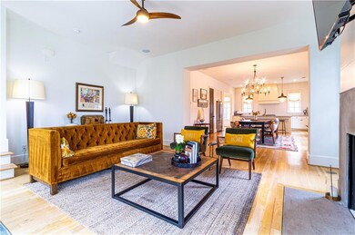 Living room with ceiling fan with notable chandelier and light hardwood / wood-style floors