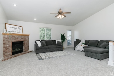 Carpeted living area with a ceiling fan, lofted ceiling, a fireplace, and recessed lighting