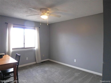 Unfurnished office with carpet flooring, a ceiling fan, and a textured ceiling