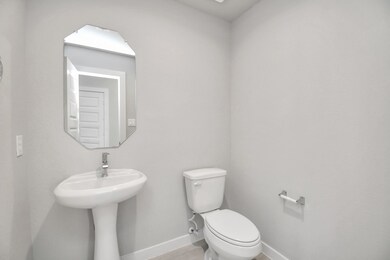 This half bathroom features a stylish pedestal sink, modern hardware, and bright recessed lighting, creating a sleek and inviting space. Sample photo of completed home with similar floor plan. Actual colors and selections may vary.
