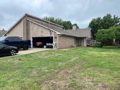 View of side of property featuring a garage, brick siding, concrete driveway, and a chimney