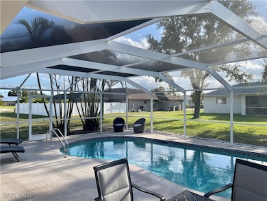 Swimming pool featuring a lanai, a lawn, a patio a
