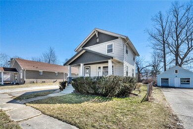 View of front of home featuring a porch, a garage, an outbuilding, and a front lawn
