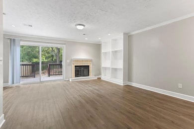 Unfurnished living room with a tiled fireplace, dark wood-type flooring, a textured ceiling, and crown molding