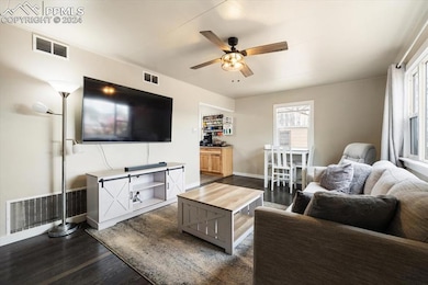 Living room with ceiling fan and dark wood-type fl