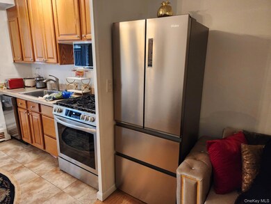 Kitchen with stainless steel appliances, light countertops, light tile patterned flooring, and brown cabinets