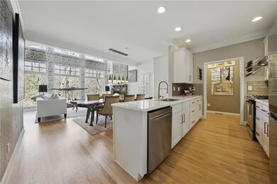 Kitchen with a sink, appliances with stainless steel finishes, ornamental molding, light wood-type flooring, and white cabinets