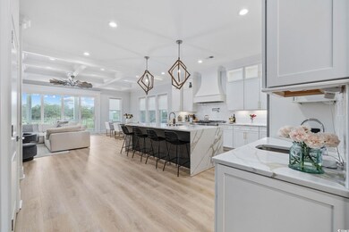 Kitchen featuring premium range hood, recessed lighting, open floor plan, a kitchen bar, and coffered ceiling