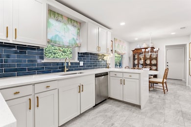 Kitchen featuring tasteful backsplash, white cabinetry, a peninsula, recessed lighting, and light stone counters