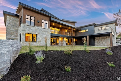 Back of property featuring a balcony and stone siding, gorgeous landscaping
