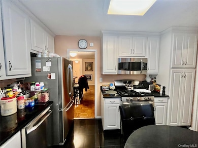 Kitchen featuring white cabinetry, appliances with stainless steel finishes, and dark tile patterned floors