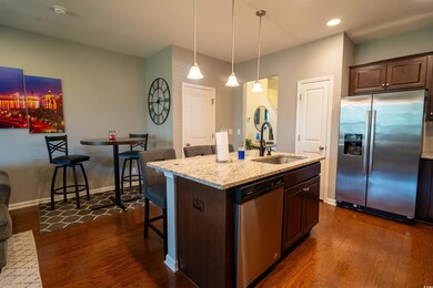 Kitchen featuring appliances with stainless steel finishes, a sink, dark wood-type flooring, a breakfast bar area, and light stone counters