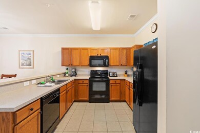 Kitchen featuring black appliances, brown cabinetry, light tile patterned floors, light countertops, and ornamental molding