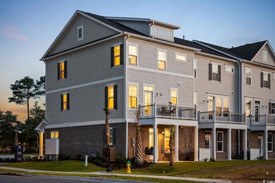 Rear view of house with brick siding, a yard, and a balcony