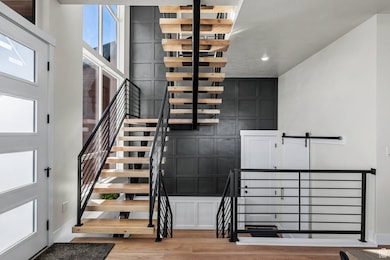 Stairway featuring wood finished floors and an accent wall