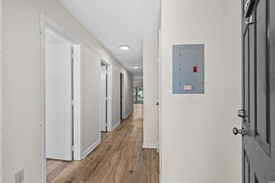 Hallway with baseboards, electric panel, and light