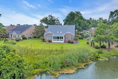 Back of property with a sunroom, brick siding, a lawn, and a water view
