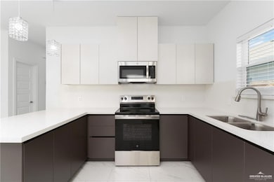 Kitchen with stainless steel appliances, marble finish floor, modern cabinets, and a sink