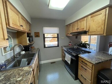 Kitchen featuring gas stove, dark countertops, under cabinet range hood, light brown cabinetry, and dishwasher