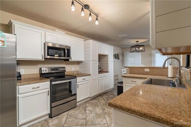 Kitchen with appliances with stainless steel finishes, white cabinets, pendant lighting, and track lighting