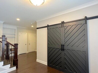 Corridor featuring a barn door, crown molding, dark wood finished floors, recessed lighting, and baseboards