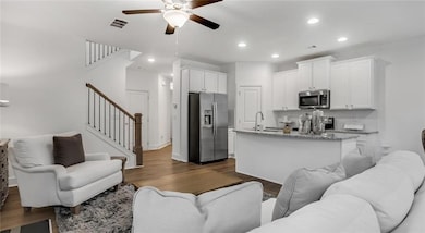 Living area featuring ceiling fan, stairway, dark wood-type flooring, and recessed lighting