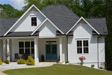 Modern farmhouse style home featuring board and batten siding, a shingled roof, a porch, and a front yard