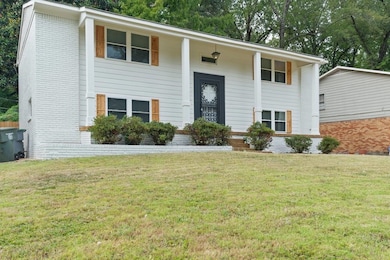 Bi-level home with brick siding, a front lawn, and a porch