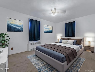 Bedroom with radiator heating unit, carpet floors, and ceiling fan