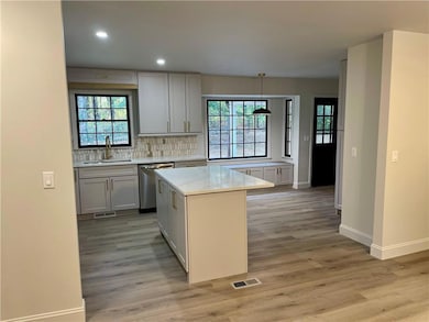 Kitchen featuring decorative backsplash, recessed lighting, dishwasher, light wood-type flooring, and light stone counters