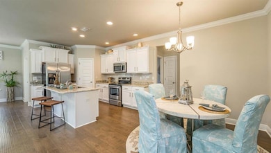 Kitchen with stainless steel appliances, crown molding, white cabinetry, tasteful backsplash, and a chandelier