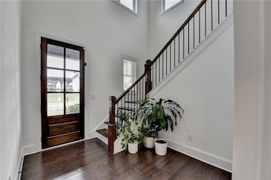 Entryway with stairway, baseboards, a high ceiling