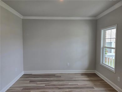 Unfurnished room with ornamental molding, wood finished floors, and baseboards