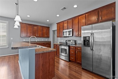 Kitchen with appliances with stainless steel finishes, dark wood-style floors, recessed lighting, and hanging light fixtures